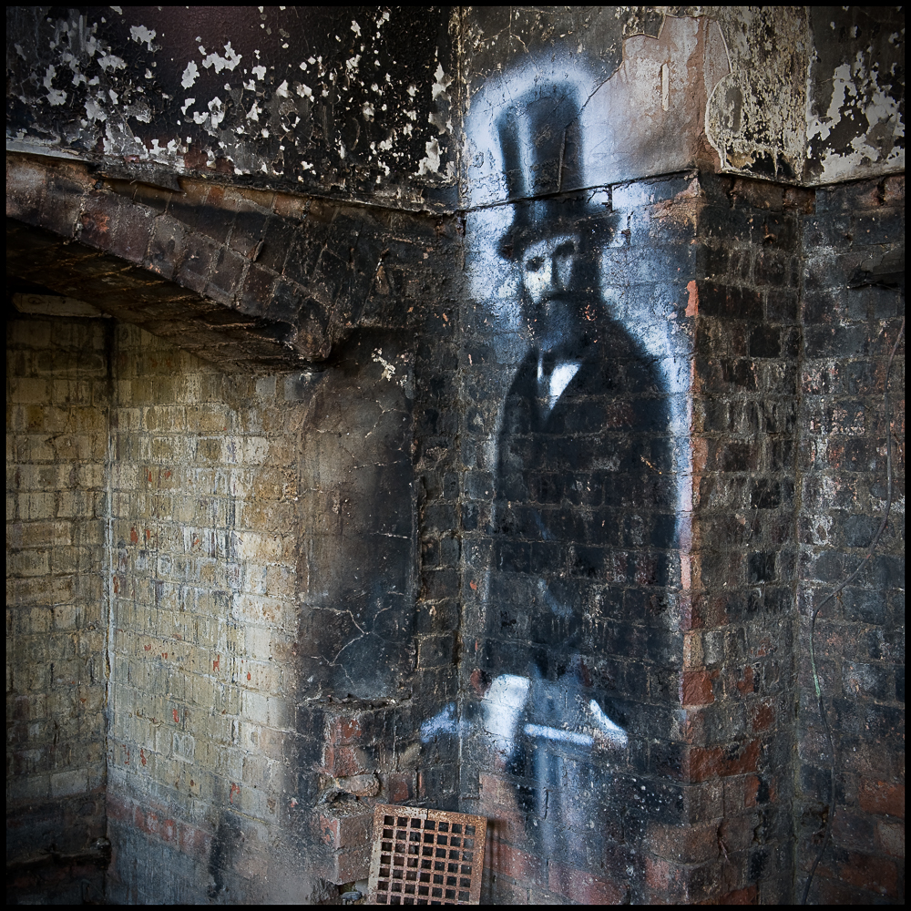 Man in top hat painted on wall of derelict Hellingly Asylum by artist Req, West Sussex