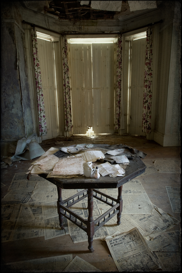 Table in room, papers on table and floor, closed shutters, derelict Manor House 'B', Norfolk, UK