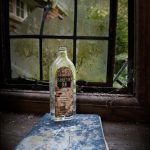 Empty bottle on a book by a window, derelict house